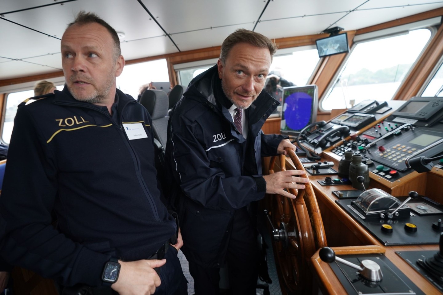 Finanzminister Christian Lindner (r) steuert das Zollboot «Kehrwieder», links Zollkapitän Steffen Molter.
