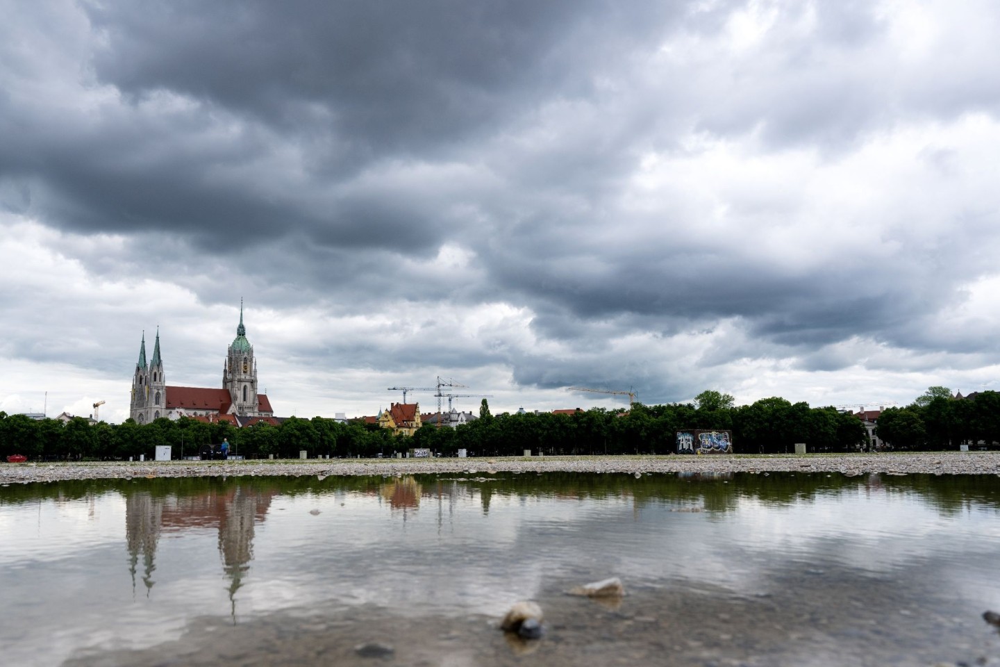 Dunkle Wolken ziehen über Theresienwiese in München. Im Hintergrund steht die Kirche St. Paul.