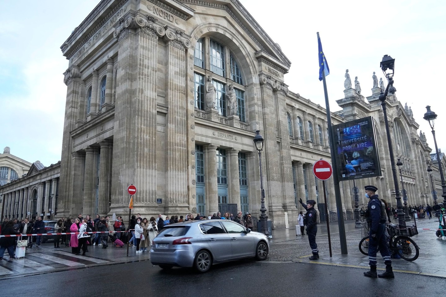 Menschen warten hinter einer Polizeiabsperrung vor dem Bahnhof Gare du Nord in Paris.