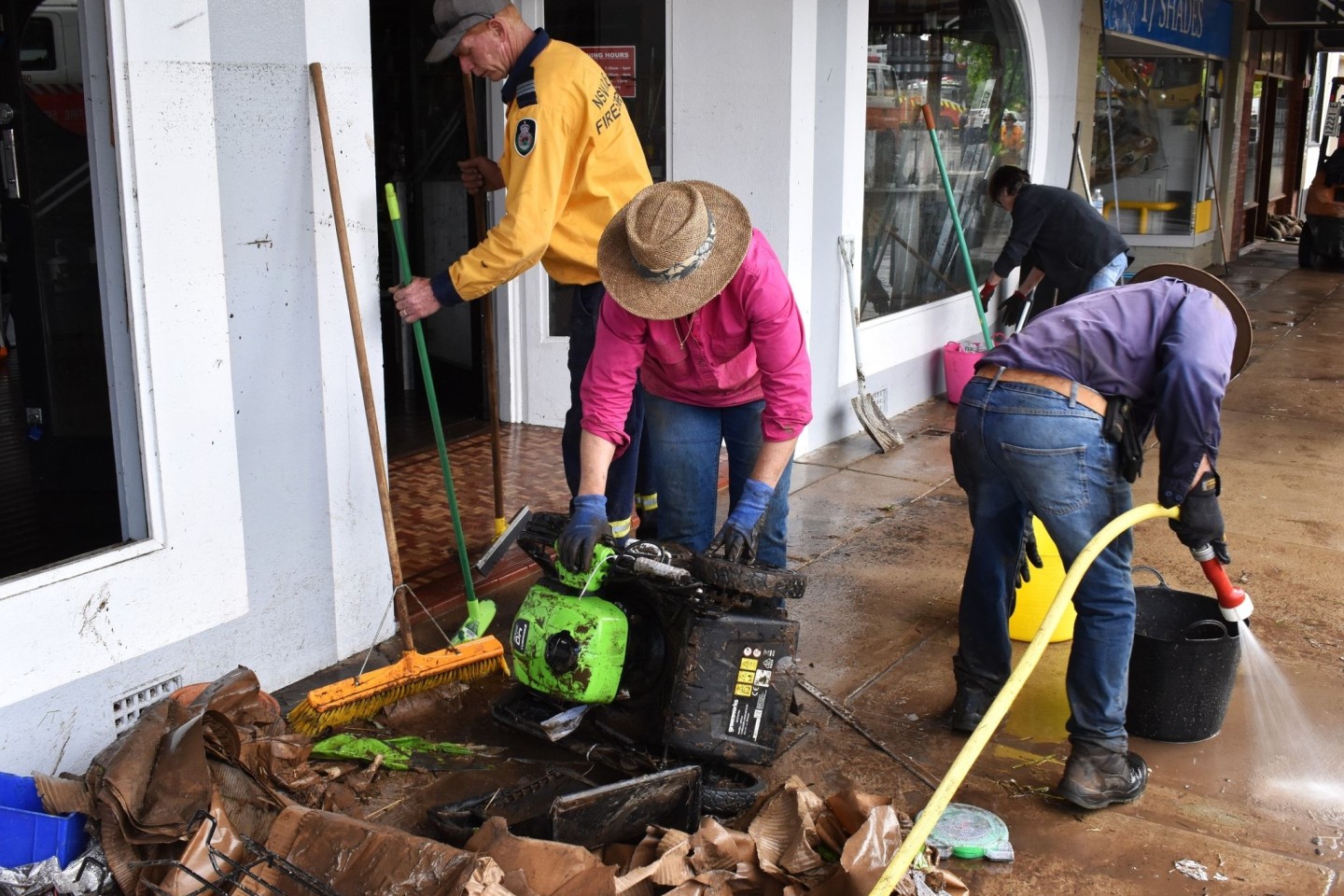 Freiwillige Helfer und Geschäftsinhaber beseitigen nach den Überschwemmungen in der Stadt Molong in der Region Central West von New South Wales Trümmer und Schlick aus den Gebäuden.