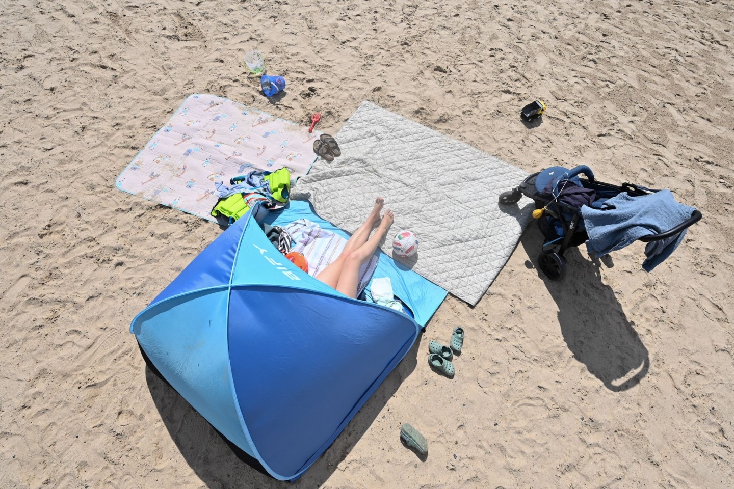 Eine Frau genießt in ihrer Sonnenmuschel das Sommerwetter am Badesee.